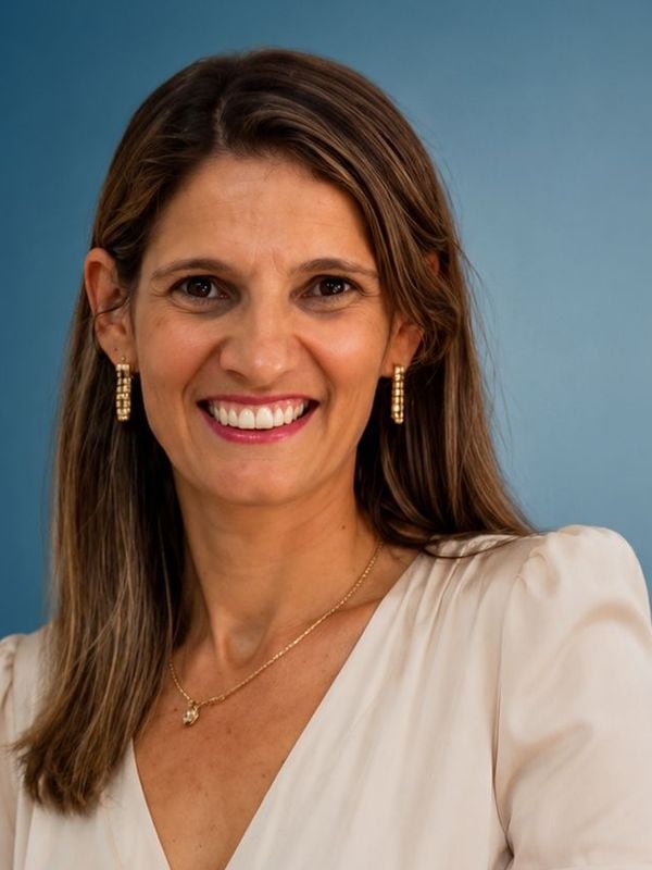 Retrato institucional de uma mulher com cabelos castanhos e roupa clara